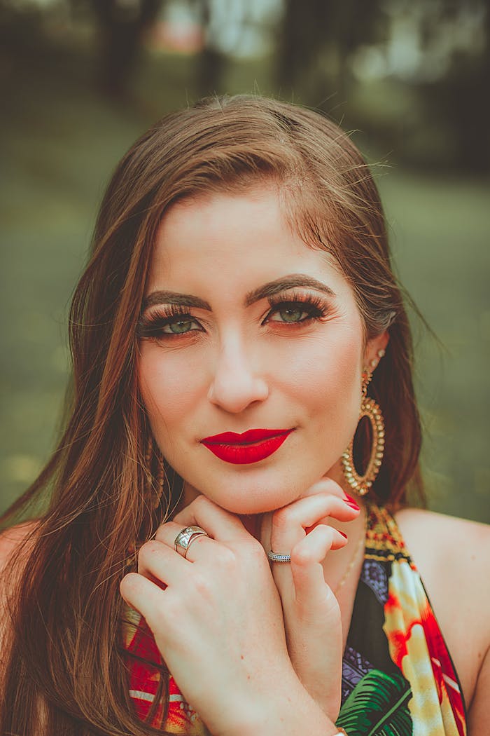 Close-up portrait of a stylish woman with red lips and jewelry posing outdoors.